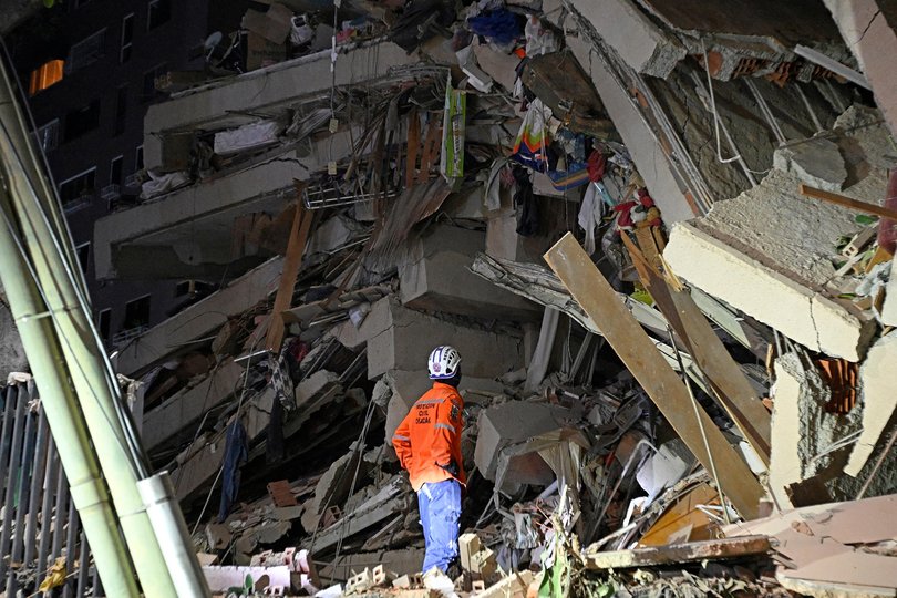 A rescuer looks at the rubble of a collapsed building.
