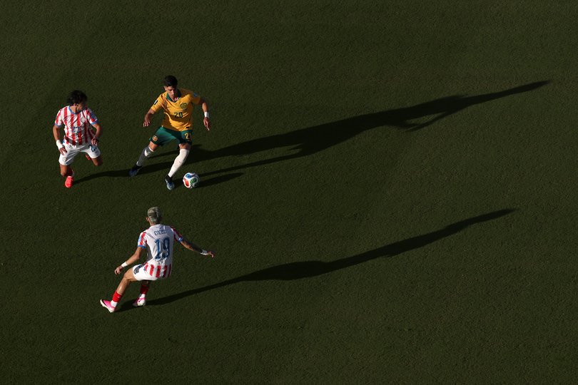 Cristian Volpato #20 of Australia controls the ball against Julio Enciso #19 and Matias Galarza #23 of Paraguay.