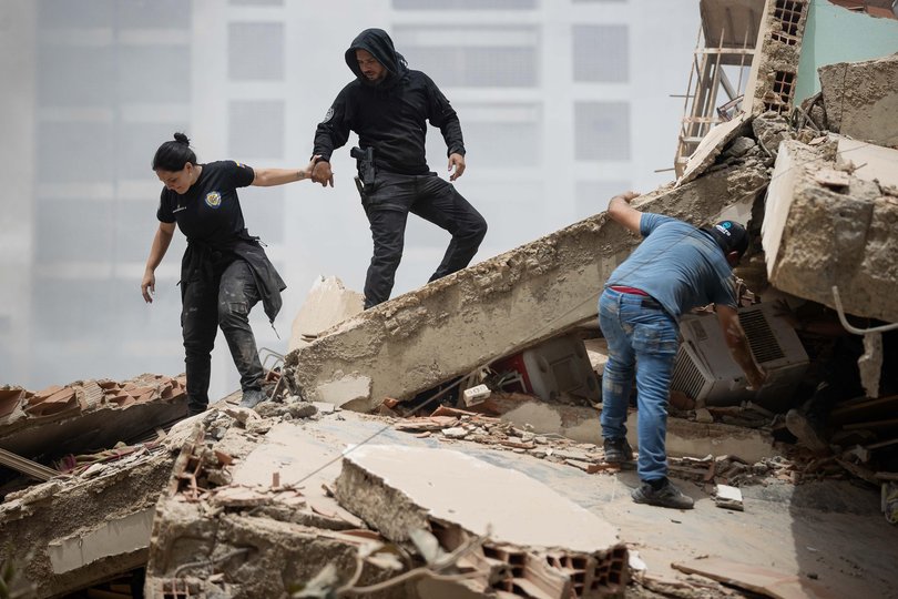 People walk among the rubble of collapsed buildings in La Guaira, Venezuela.