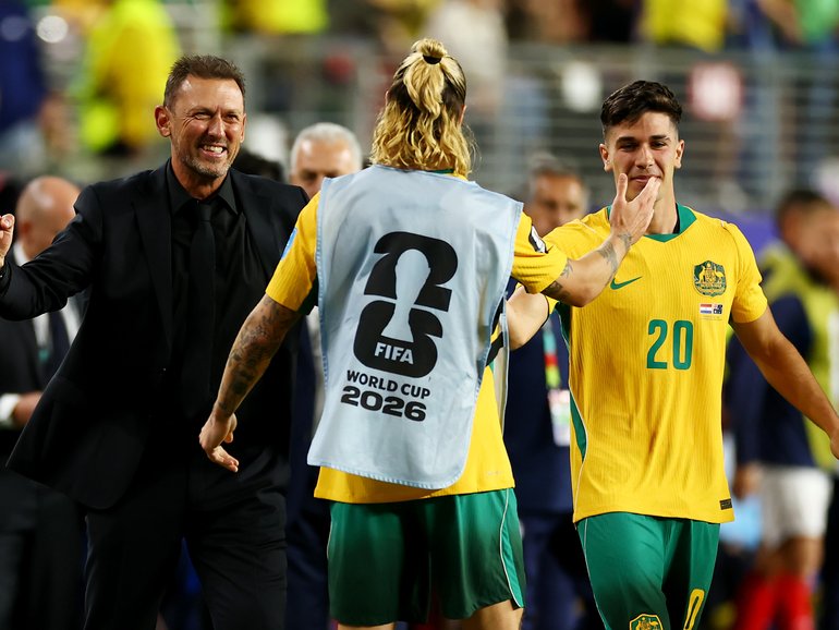 Tony Popovic, Head Coach of Australia, Cristian Volpato #20, and Jackson Irvine #22 celebrate after a 0-0 draw.