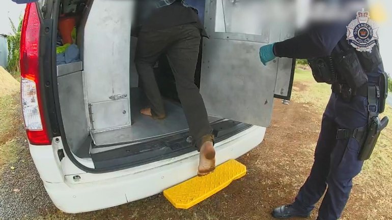 A man steps into a police van after being charged with the murder and torture of a baby boy. (HANDOUT/QUEENSLAND POLICE)