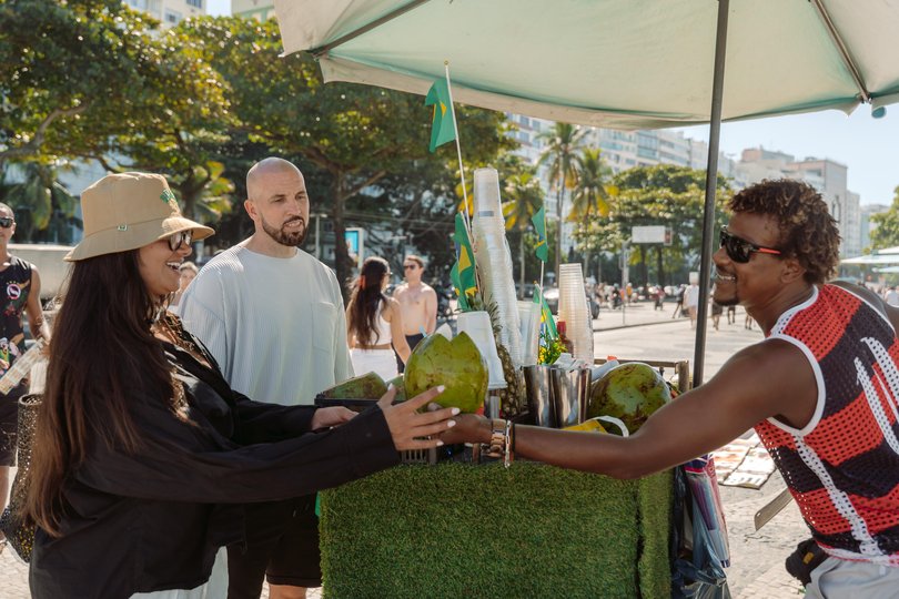 Laert Temuda sells a fresh coconut on the Copacabana Beach boardwalk to a British couple. 
