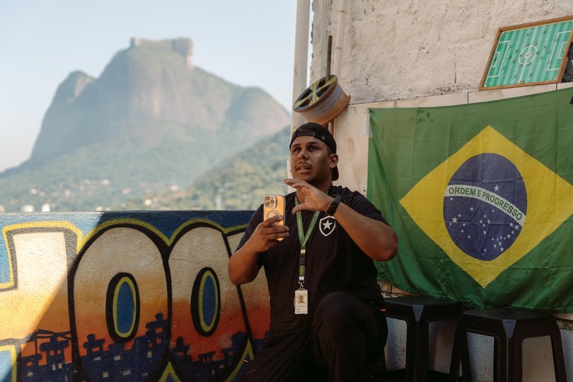 Rocinha tour guide Carlos Alberto Soares da Silva captures photos of his tour group on a rooftop. 