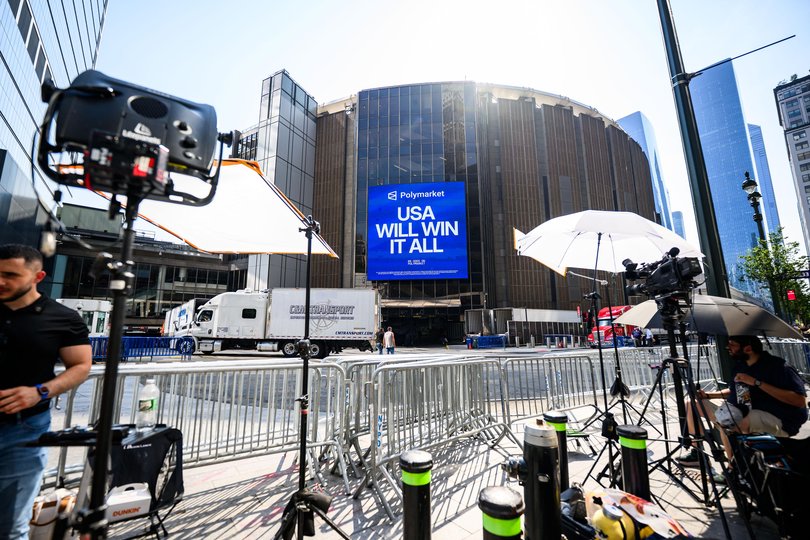 Media representatives are standing behind barriers in front of Madison Square Garden.