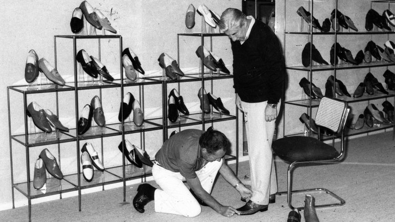 Ray Ashby, manager of Betts and Betts men’s department fitting a customer’s new shoes in 1983.