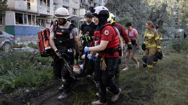 Ukrainian Red Cross members carry an injured resident from a collapsed residential building after a missile attack by Russian forces.