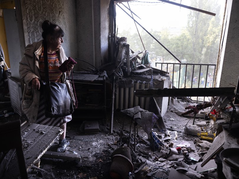 An elderly woman goes back to her apartment to see the destruction after a Russian missile hit the residential building.