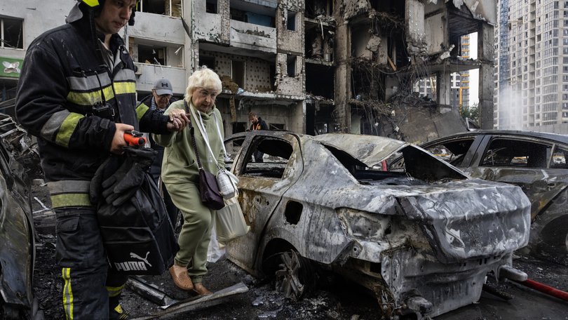 Ukrainian firefighters evacuate an elderly woman from the scene of an attack as Russian missiles and drones struck Kyiv overnight on Monday.