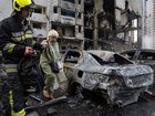 Ukrainian firefighters evacuate an elderly woman from the scene of an attack as Russian missiles and drones struck Kyiv overnight on Monday.
