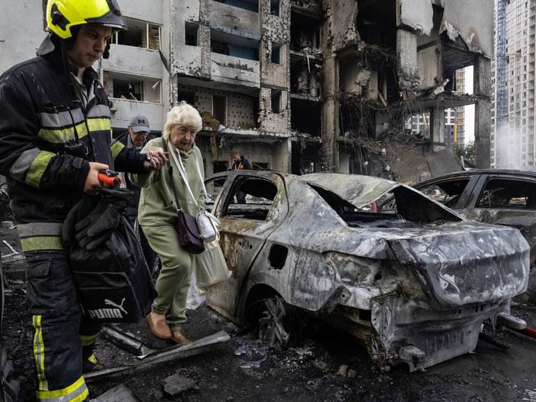Ukrainian firefighters evacuate an elderly woman from the scene of an attack as Russian missiles and drones struck Kyiv overnight on Monday.