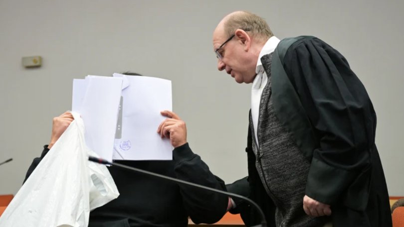 The defendant covering his face in Munich in February as he arrives for a trial against a network of men accused of using chat groups to share tips on how to drug and rape women.