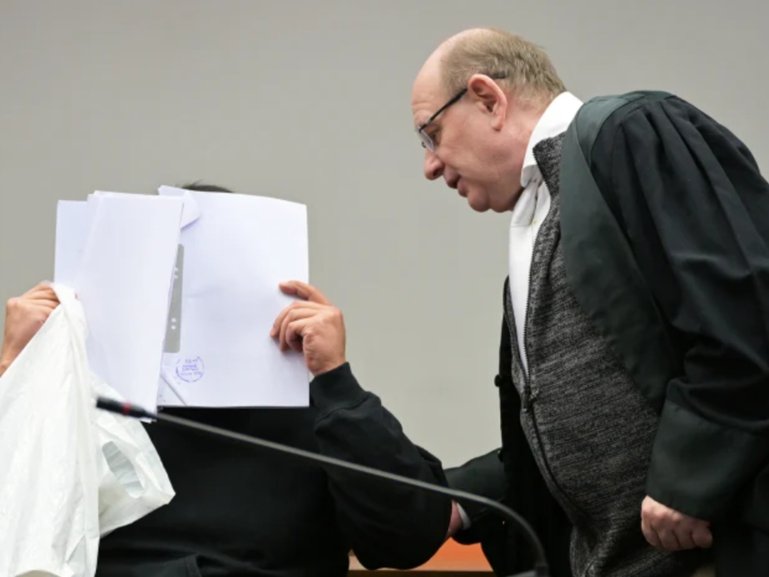 The defendant covering his face in Munich in February as he arrives for a trial against a network of men accused of using chat groups to share tips on how to drug and rape women.