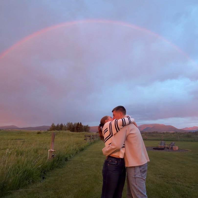 A rainbow formed a perfect arc over them as they embraced.