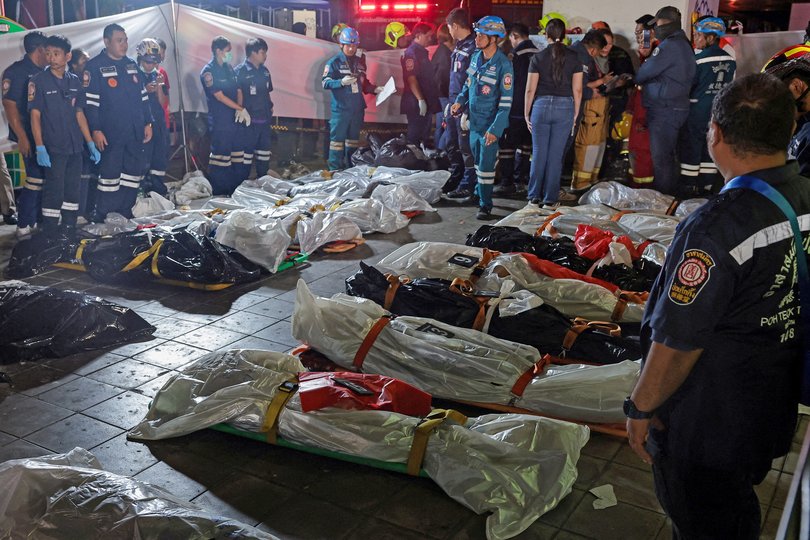 Members of emergency personnel work next to covered bodies at the site of a deadly fire at a pub in Bangkok.