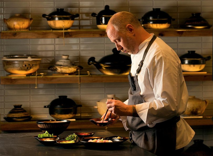 Chef Kyle Connaughton uses a Japanese donabe from his collection, at back on the wall, to cook his Tilefish, Blue Foot, and Chantrelle “Fukkura-San” with Leeks, Brassicas From the Farm, Sansho, and Chamomile Dashi Broth at Single Thread Farms Restaurant in Healdsburg. (John Burgess/The Press Democrat) John Burgess