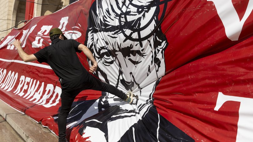 An Iranian kicks a large banner depicting Donald Trump during funeral ceremonies for Iran's slain Supreme Leader, Ayatollah Ali Khamenei.