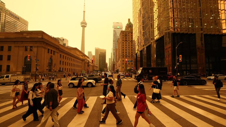 People walk in downtown Toronto, as smoke from forest fires in Northern Ontario causes poor air quality over the city.