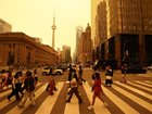People walk in downtown Toronto, as smoke from forest fires in Northern Ontario causes poor air quality over the city.