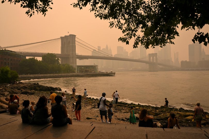 People look at the Brooklyn Bridge as wildfire smoke from Canada causes hazy conditions in New York.