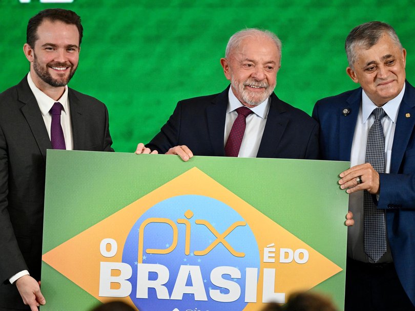Brazilian Finance Minister Dario Durigan, President Luiz Inacio Lula da Silva, and Institutional Relations minister Jose Guimaraes pose with a banner reading ‘Pix is from Brazil’.