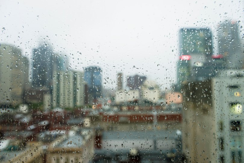 Raindrops on a window looking out to gloomy, overcast weather in Melbourne, Australia.