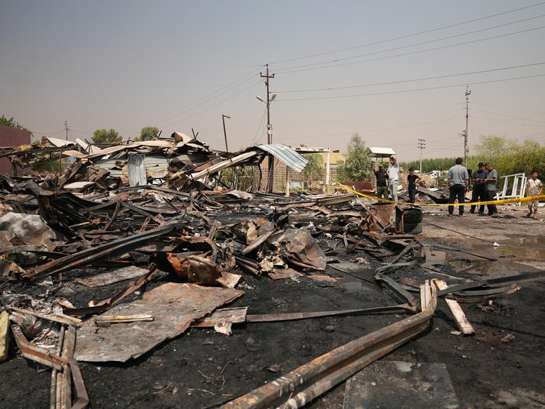 Iraqis inspect damaged structures at the site of an airstrike on a Popular Mobilization Forces base in Mosul, Iraq.