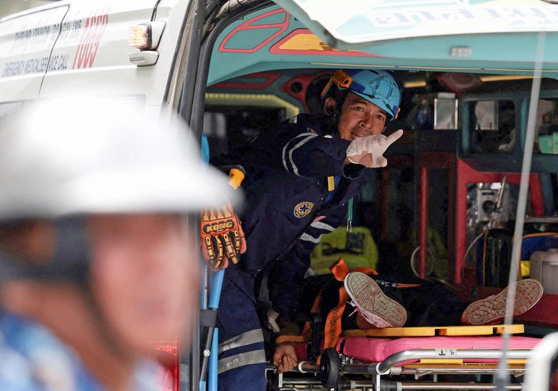 An injured teacher lies in an ambulance.