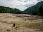 People walk along the exposed lake bottom of the severely shrunk Nussensee mountain lake during ongoing drought in Austria.