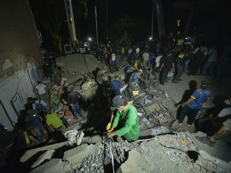 Volunteers help with debris removal at a collapsed building at Simón Bolívar square in downtown Pereira after a magnitude 7.4 earthquake struck Colombia.