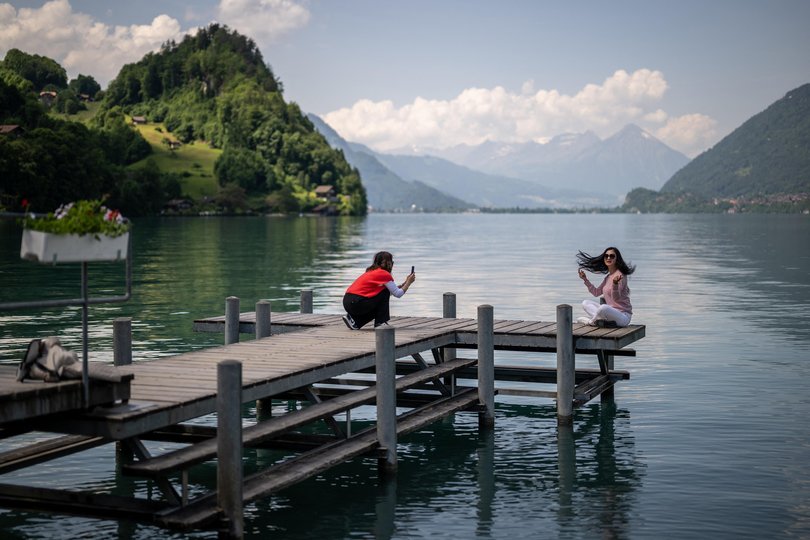 Tourists take photographs on the famous pier of a South Korean Netflix serie in the village of Iseltwald at the shore of Lake Brienz, in the Swiss Alps.