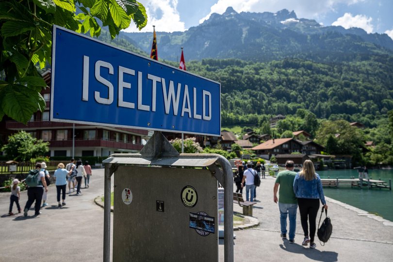 Tourists walk past a sign of Iseltwald at the shore of Lake Brienz.