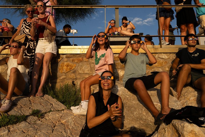 Holidaymakers using solar eclipse sunglasses to observe the total solar eclipse on August 12, 2026 in L'Escala, Spain.