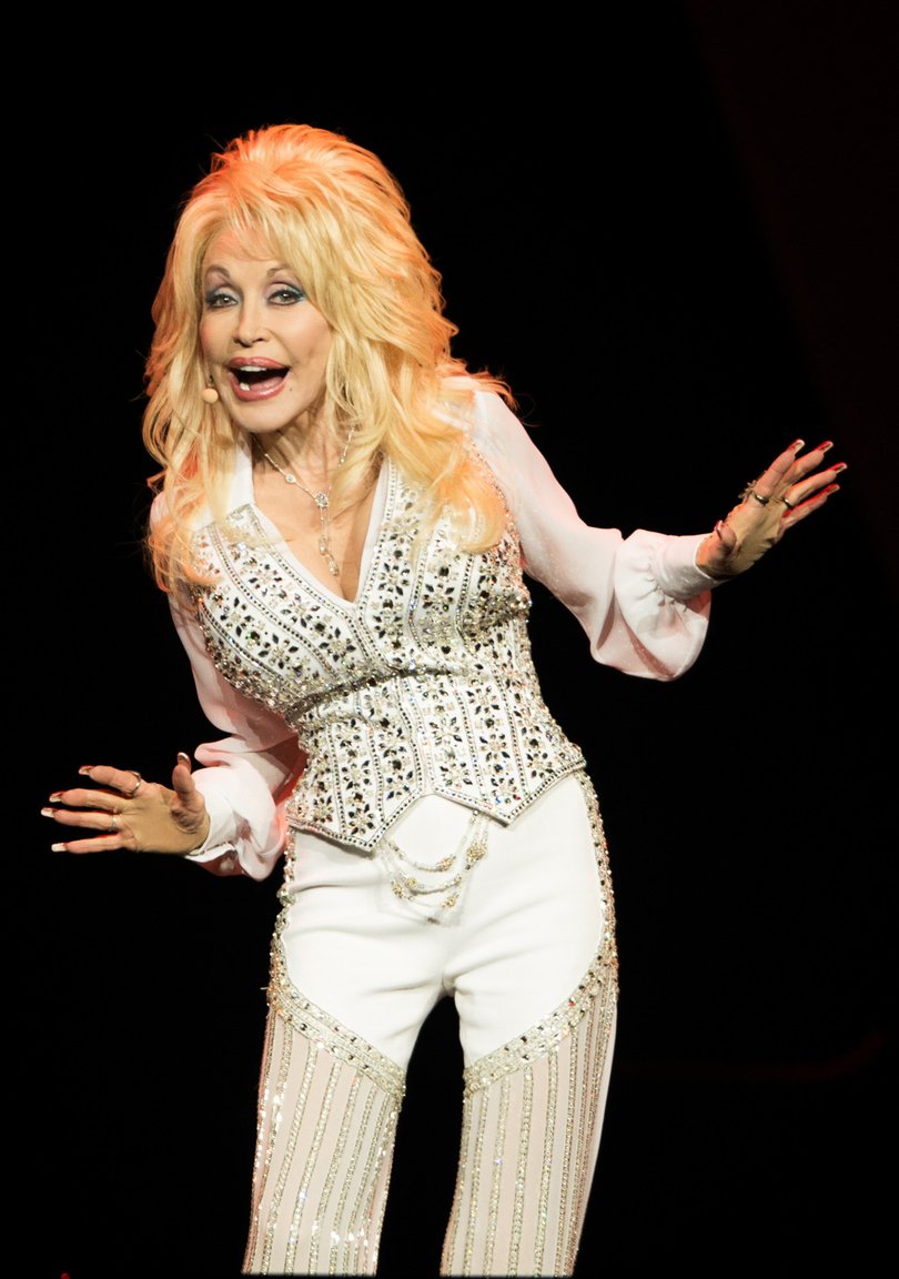 Dolly Parton in concert, wearing a rhinestone-covered outfit.
