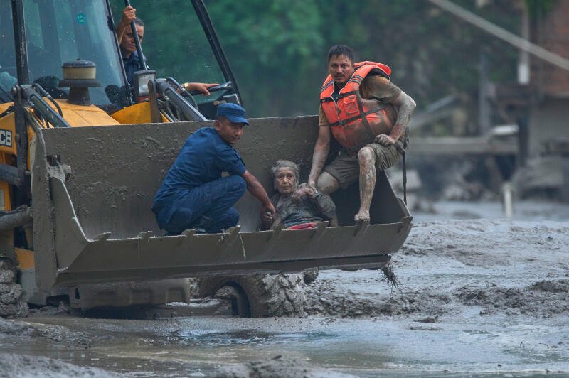 Rescuers use an earthmover to carry a victim of flash flooding to safety along the Trishuli River in Nepal's Nuwakot district.