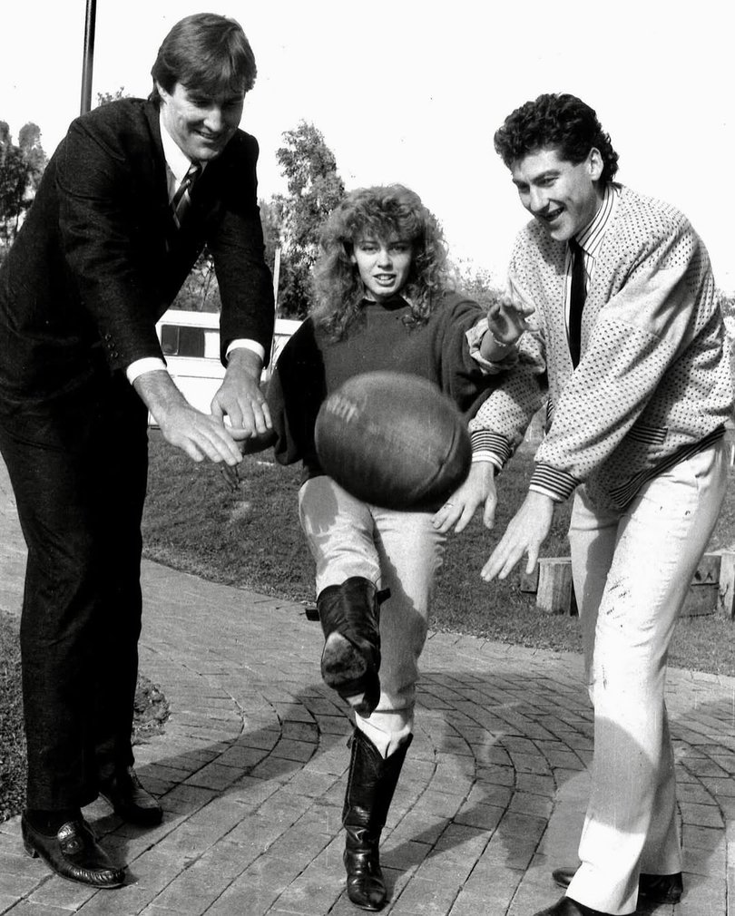 In 1986, while starring on Neighbours, Kylie performed at a Fitzroy Football Club fundraising concert, with players Matt Rendell and Scott Clayton even helping showcase her “kicking style.”