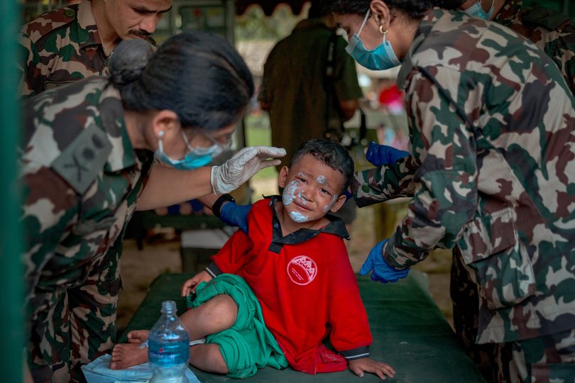 An injured child is treated at a field hospital inside a military camp, following flash floods on August 27, 2026 in Trishuli, Nepal.