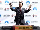 Actor Peter Cullen holds up his hands after placing them in the fabled cement during the world-famous handprint-footprint ceremony at the TCL Chinese Theatre IMAX on September 30, 2014 in Hollywood.