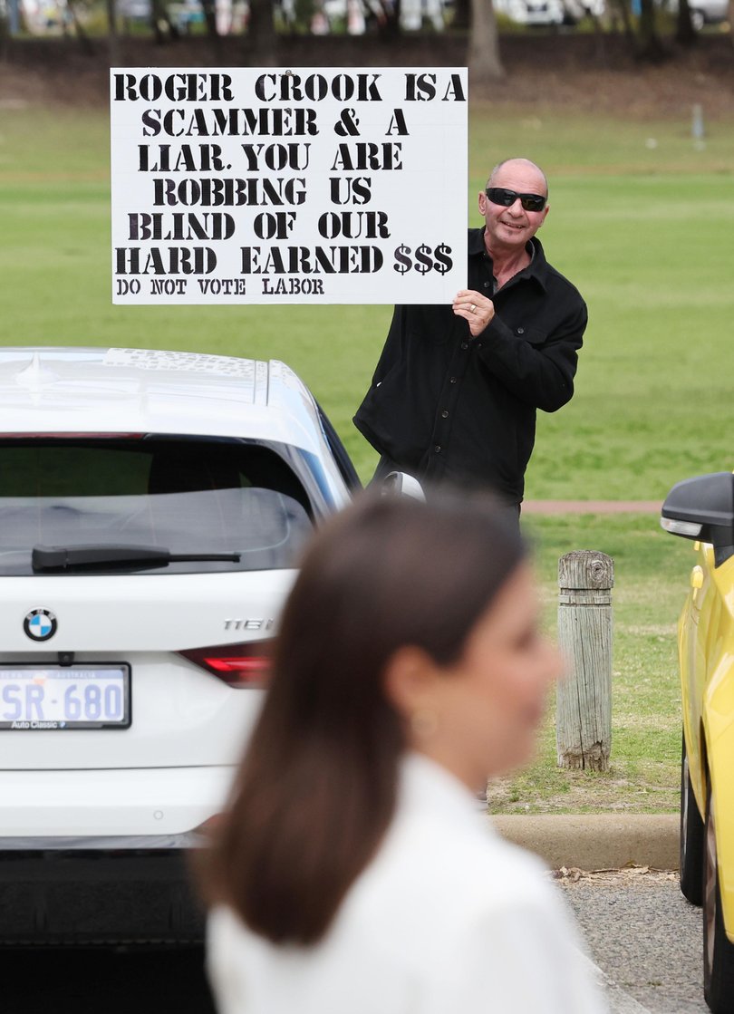 A voter holding a sign slamming Roger Cook.