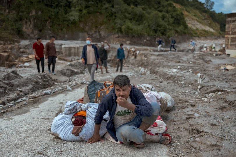 A resident sits next to belongings he recovered from his destroyed home.