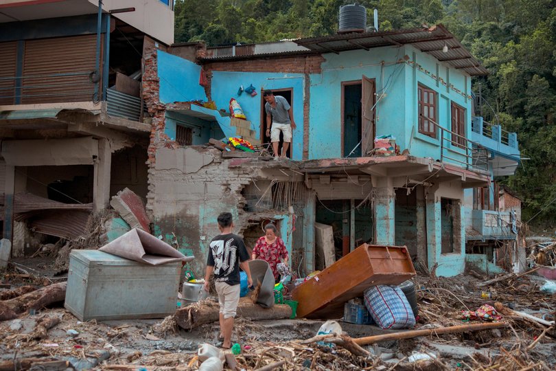 Residents salvage belongings from their destroyed home following flash floods on August 28, 2026 in Devighat, Nepal.