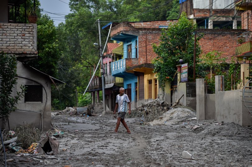 A Resident walks across debris and mud left by flash floods on August 28, 2026 in DeviGhat village, Nepal.