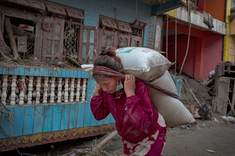 A woman carries belongings she recovered from her destroyed home.
