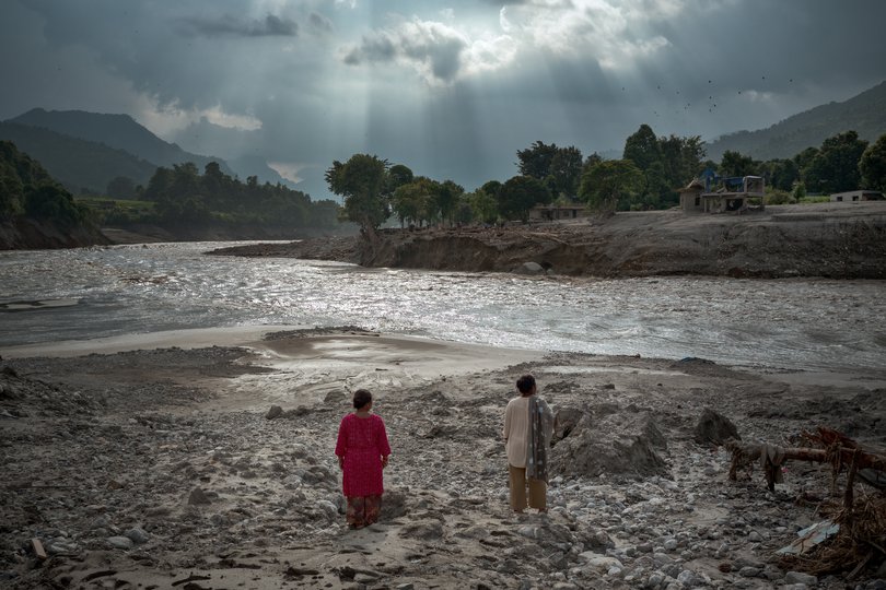 Women view the widened channel of the Trishuli River.