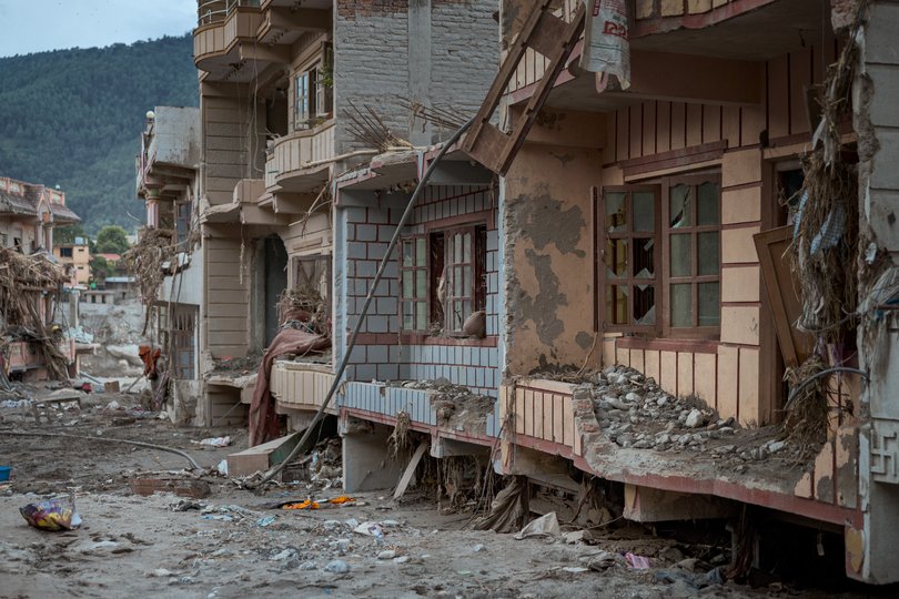 Destroyed structures are seen amid thick mud and debris.