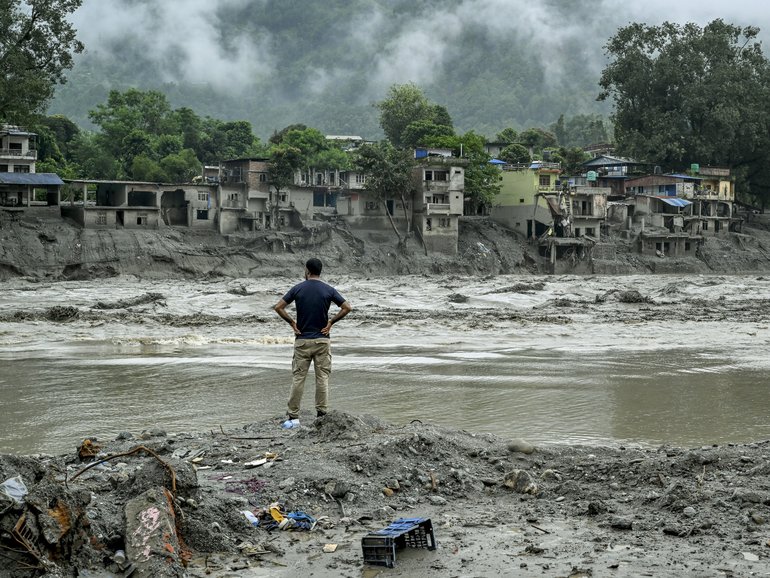 A resident surveys houses destroyed by the flash flood next to the river in Devighat, Nepal.