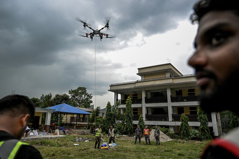 Volunteers work with police to send essential food, medicine, and other supplies for a drone relief operation in Devighat, Nepal on Saturday, Aug. 29, 2026. The drone was used to transport goods across a river to residents who are left stranded and completely cut off. (Atul Loke/The New York Times)