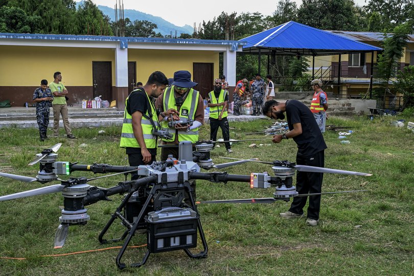 Volunteers work with police to pack essential food, medicine, and other supplies for a drone relief operation at Devighat, Nepal on Saturday, Aug. 29, 2026. The drone was used to transport goods across a river to residents who are left stranded and completely cut off. (Atul Loke/The New York Times)