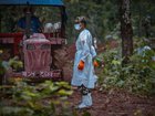 An army soldier stands by in a hazmat suit as unidentified bodies recovered from the flash floods are buried at a mass burial site in Nepal. 