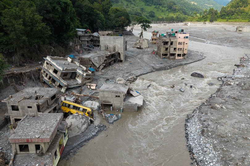 An aerial view shows a torrent of muddy water surging past houses and through the Trishuli river in the aftermath of flash floods, at Betrawati in Nepal's Nuwakot district on August 29, 2026. More than 3,000 people were listed as missing on August 30, with another 768 confirmed dead, after the flash floods and landslides that hit the Nepal-Tibet border.