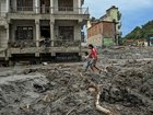 Houses damaged and partially submerged in thick mud and debris from the flood.